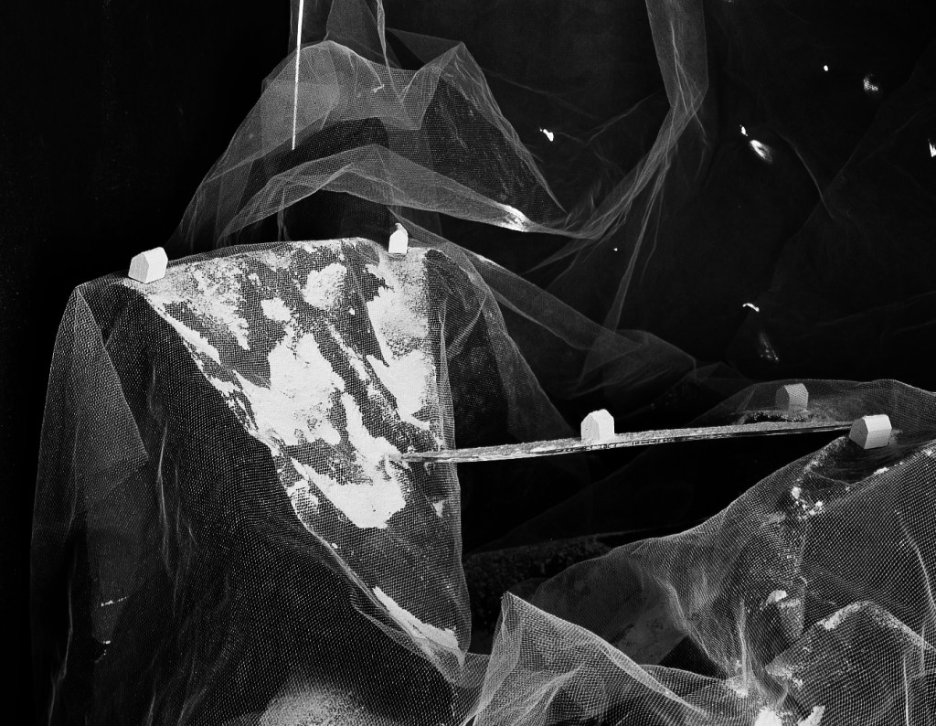 The image is a black and white photograph of a large, rectangular piece of glass or plastic with a white substance on it, ...