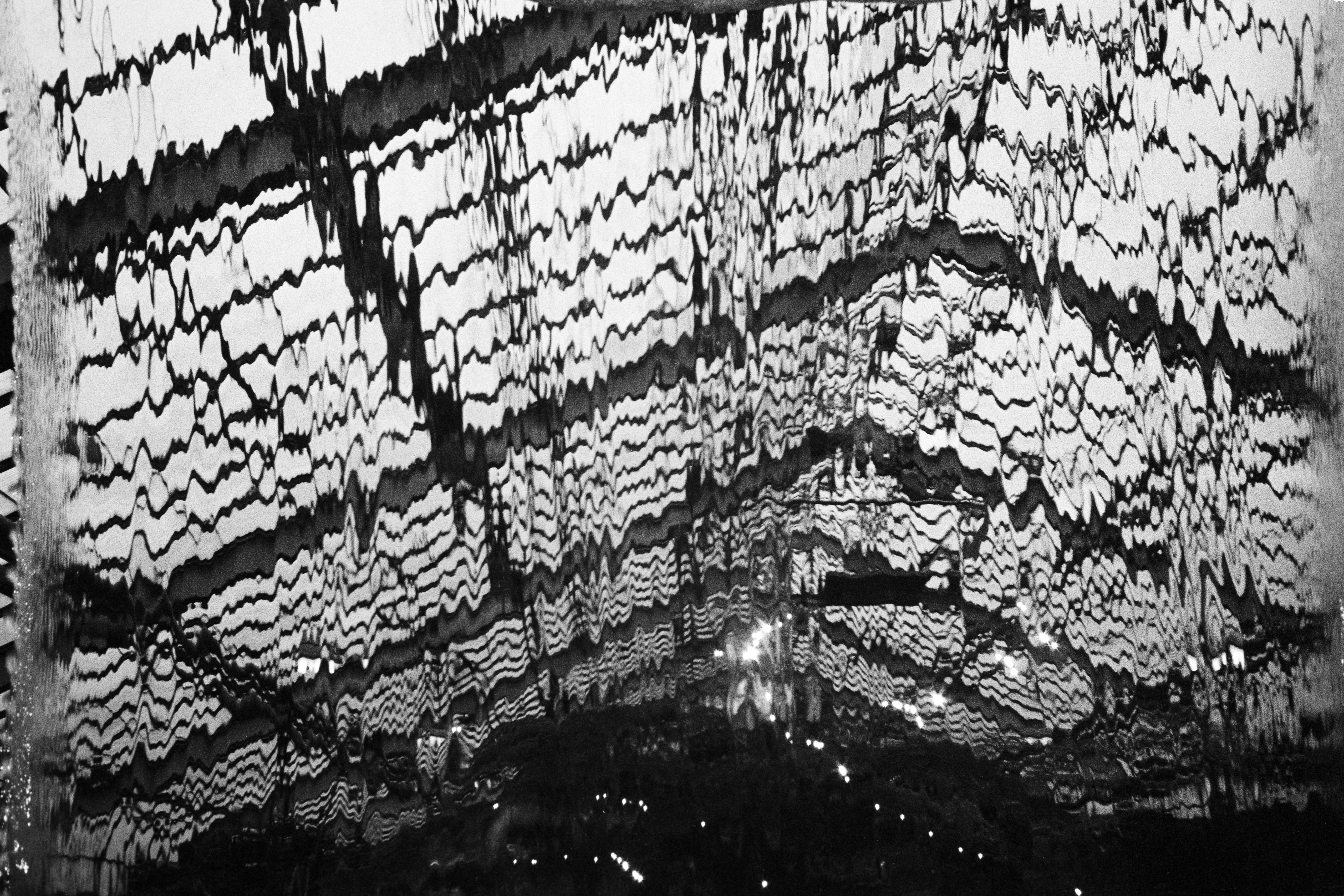 The image depicts a black and white abstract design, featuring a combination of wavy lines and shapes that evoke a sense o...